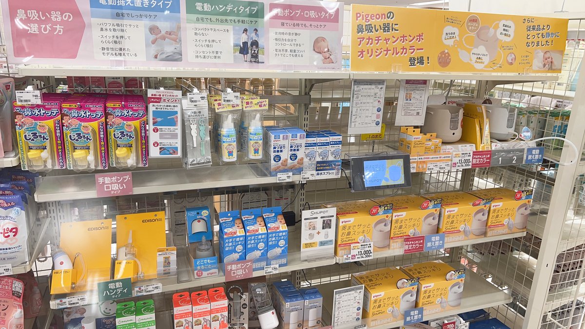 Nasal aspirator display at a Japanese baby shop, showing shelves labeled by type — electric tabletop, electric handy, and manual or mouth-suction